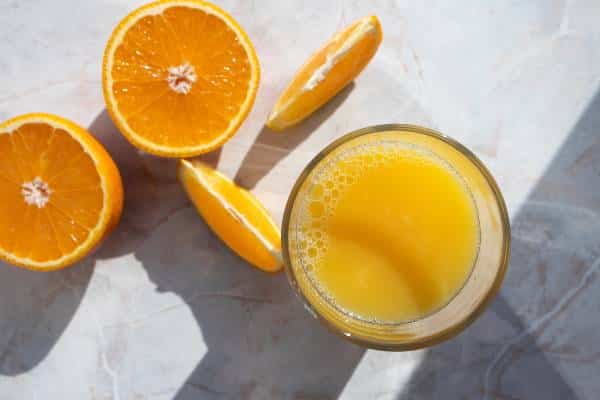 verre de jus d'orange et quartiers d'oranges